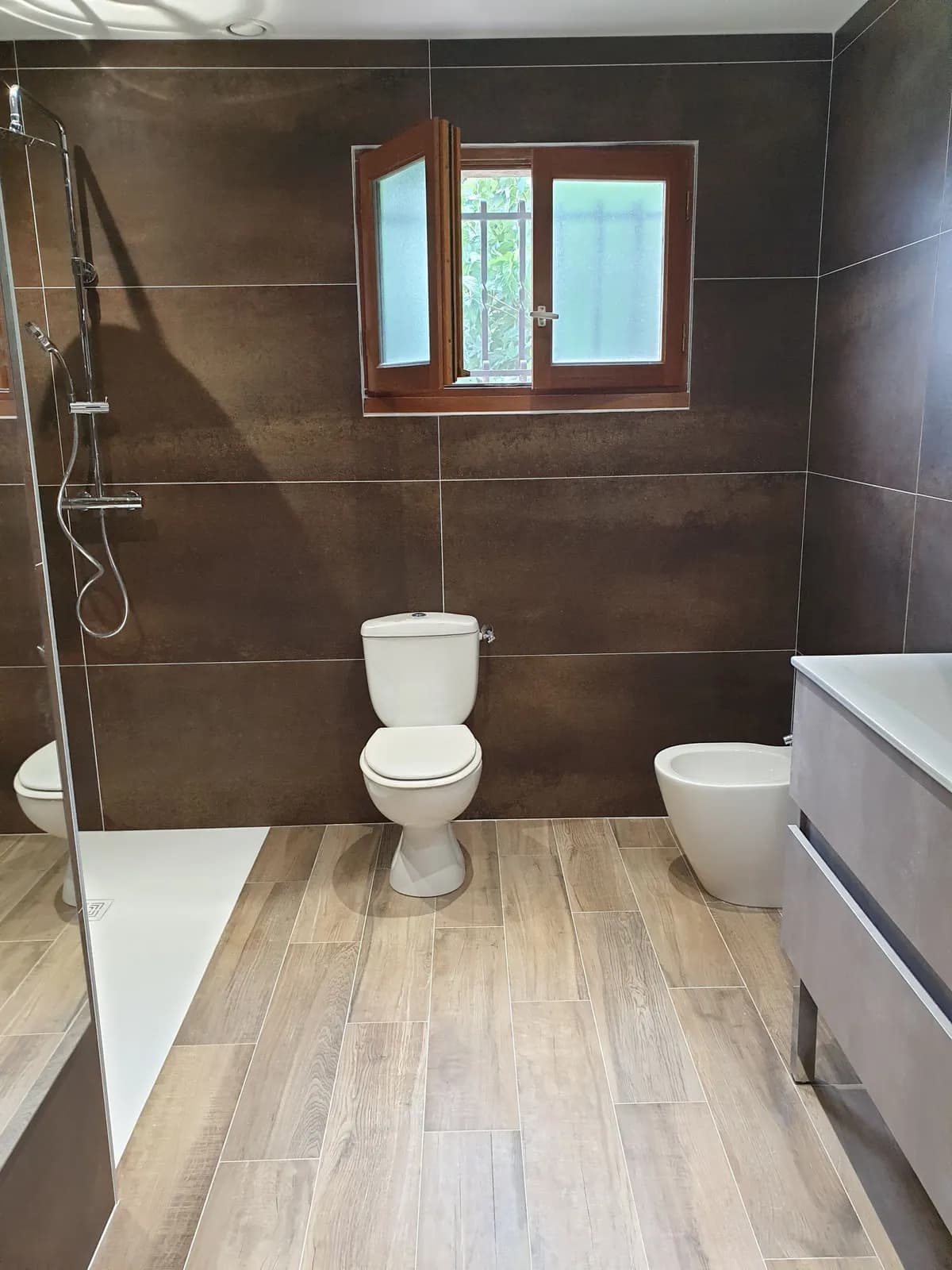 Grands carreaux bruns et sol imitation parquet dans des toilettes