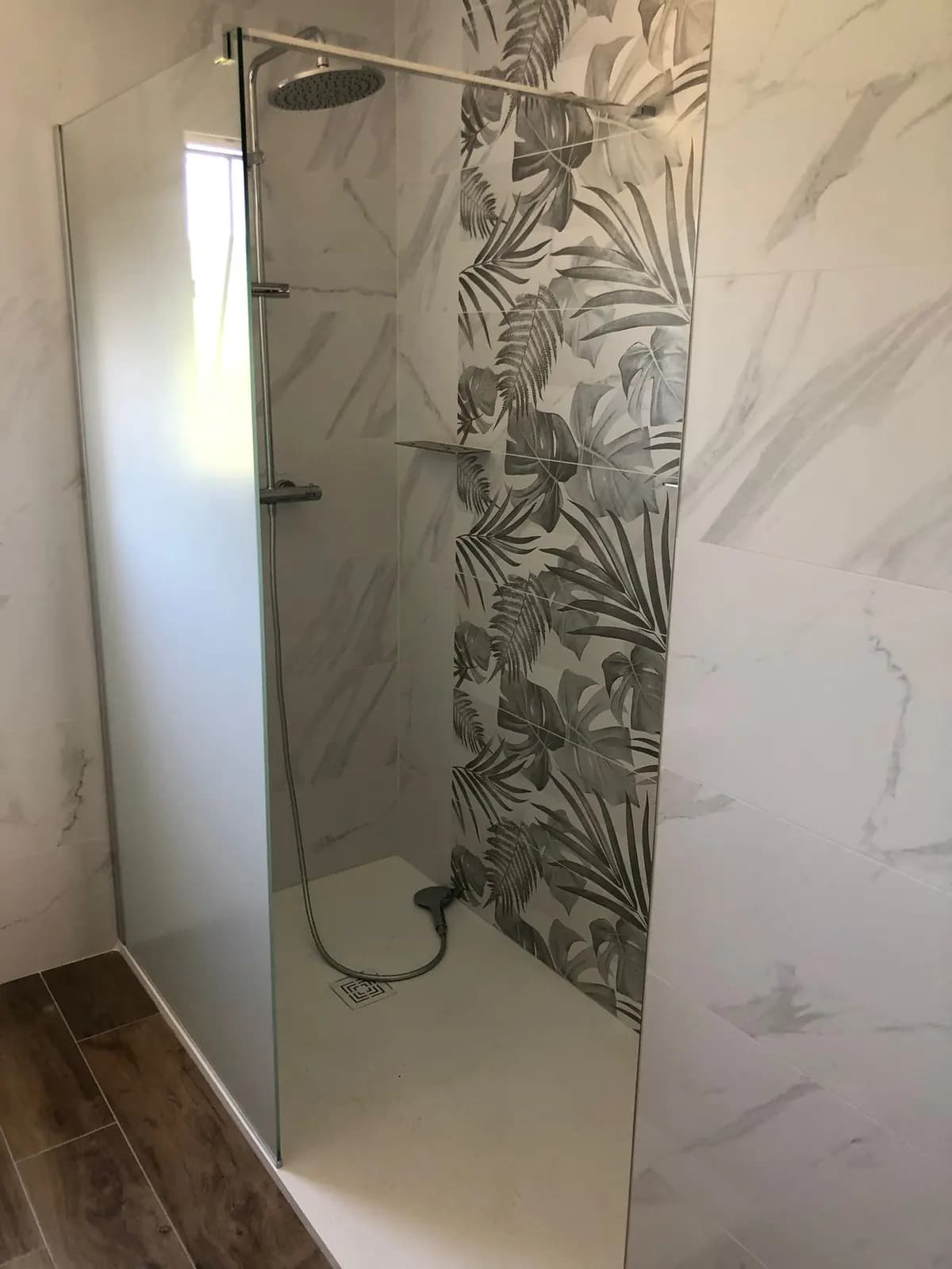 Douche avec mur en marbre et panneau de feuillages tropicaux