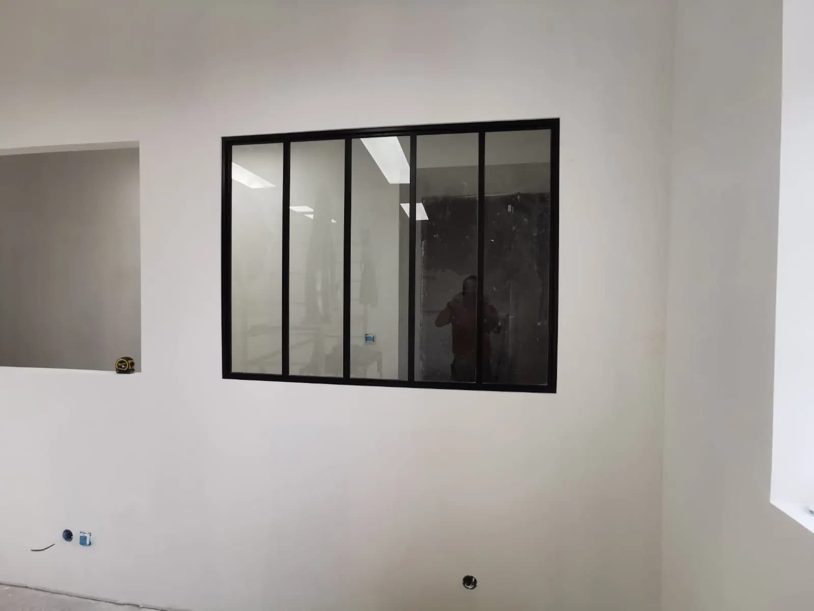 Verrière d’atelier noire à cinq panneaux dans une cloison blanche