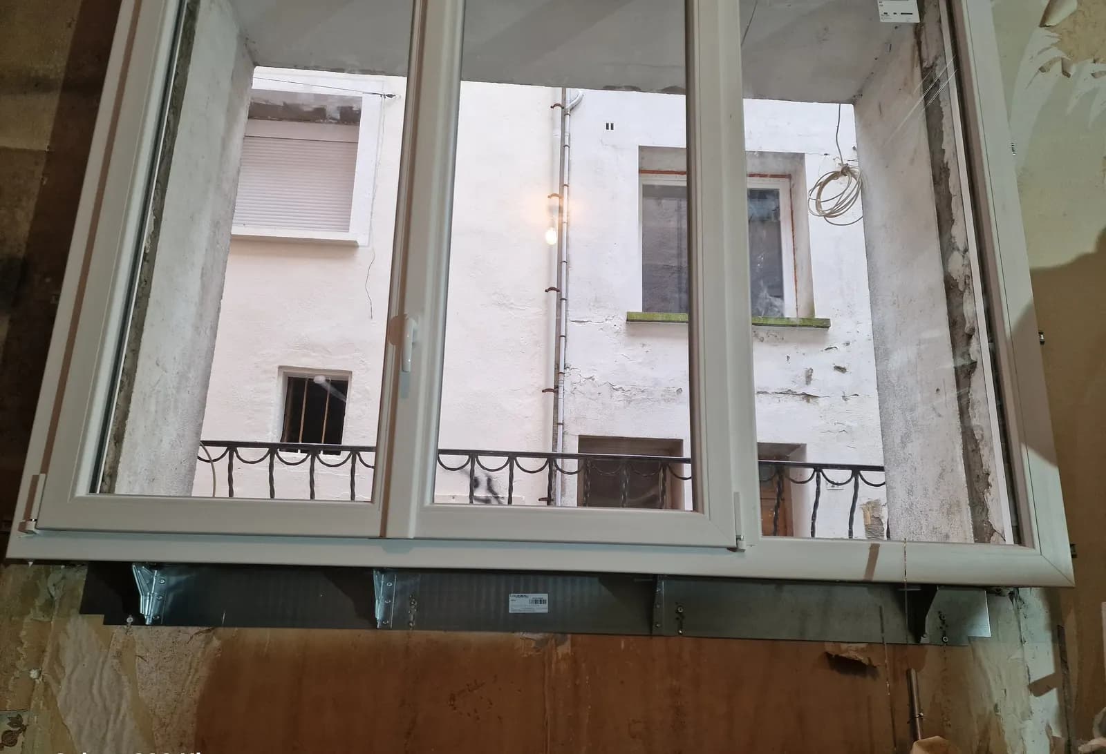 Fenêtre PVC en cours de pose, renforts métalliques sous l’appui