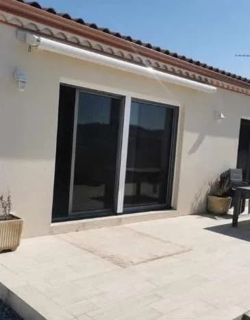Baie coulissante en aluminium anthracite posée sur une façade, avec terrasse