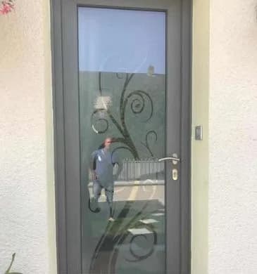 Porte d’entrée en aluminium gris avec vitrage sablé à motif de volutes