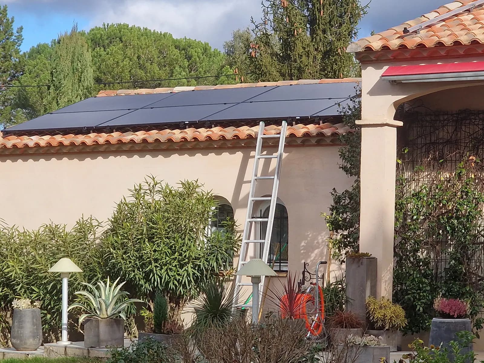 Huit panneaux photovoltaïques noirs posés sur le toit d’une annexe en tuiles