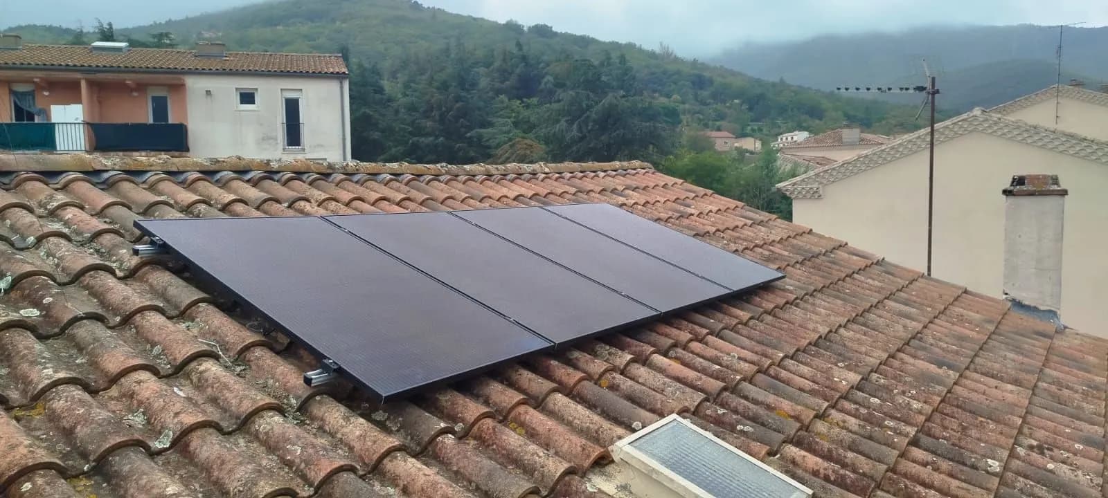 Quatre panneaux photovoltaïques posés sur un toit de tuiles de village