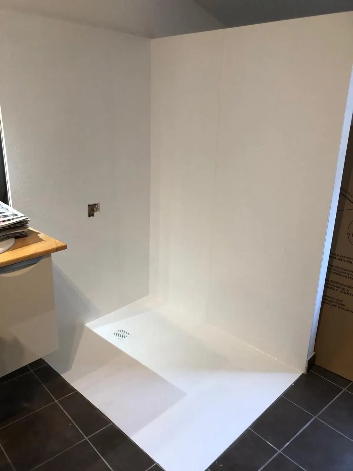 Panneaux muraux blancs et receveur extra-plat posés, sortie d’eau en attente