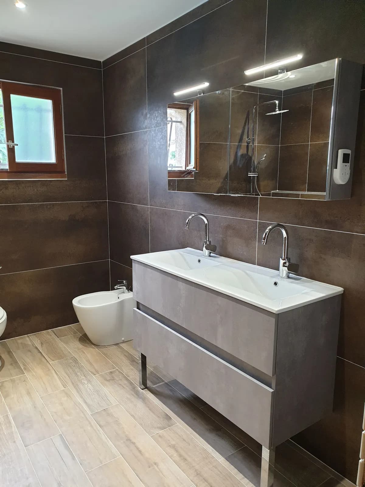 Salle de bain rénovée : double vasque sur meuble gris, armoire miroir à LED et murs brun métallisé