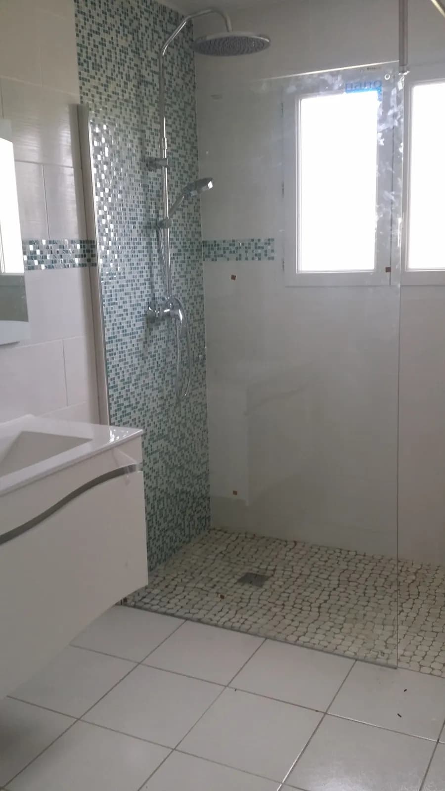 Douche à l’italienne au sol en galets et mur de mosaïque turquoise
