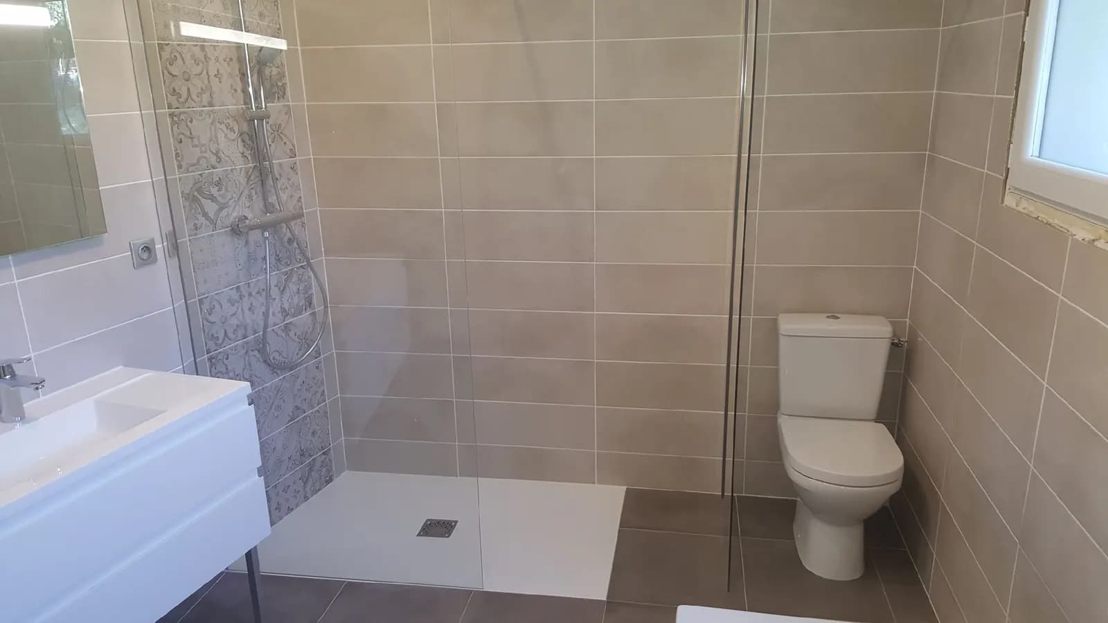 Douche à l’italienne avec bande de carreaux de ciment, WC et meuble vasque