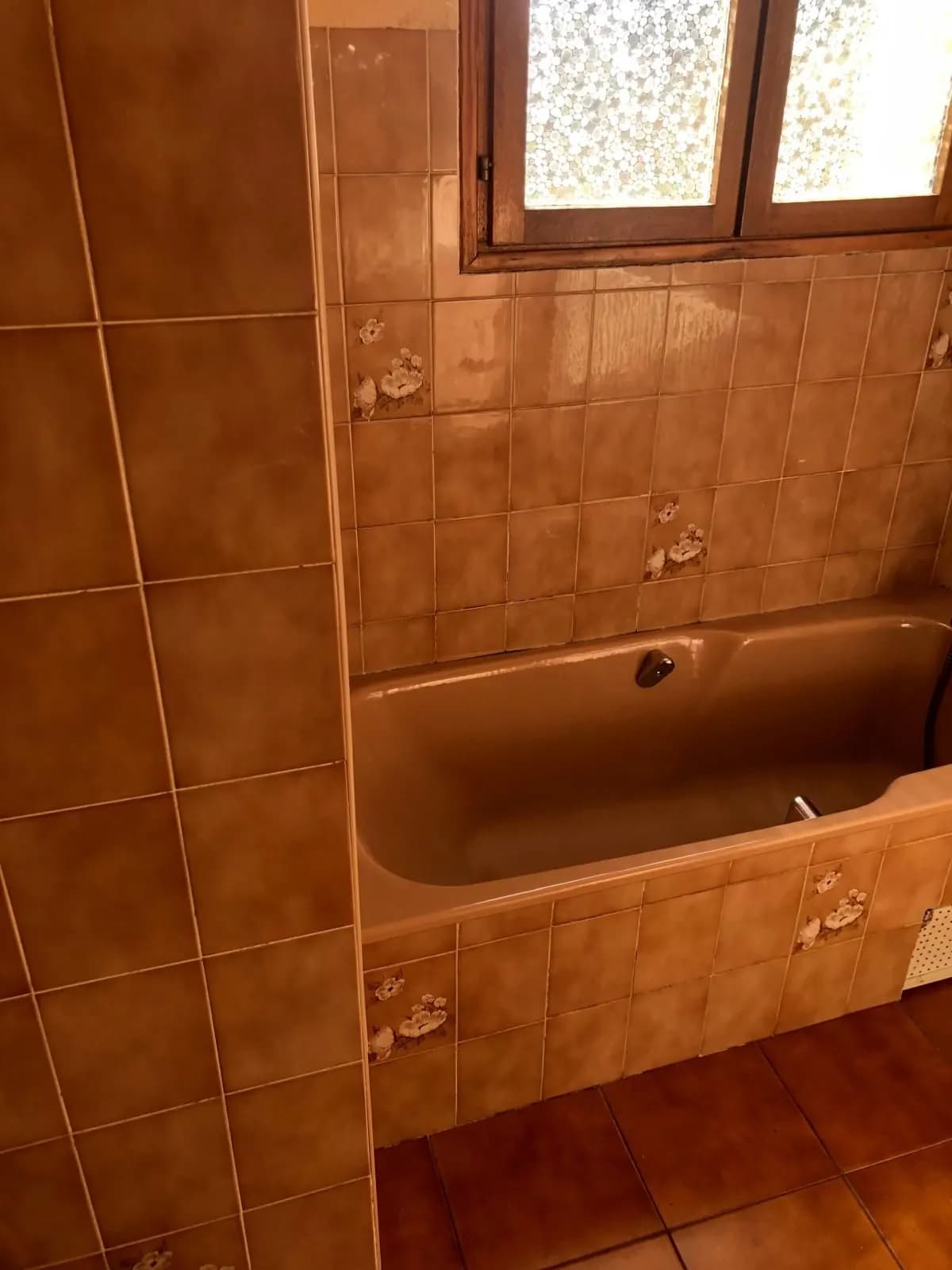 Salle de bain avant travaux : baignoire beige et faïence à fleurs
