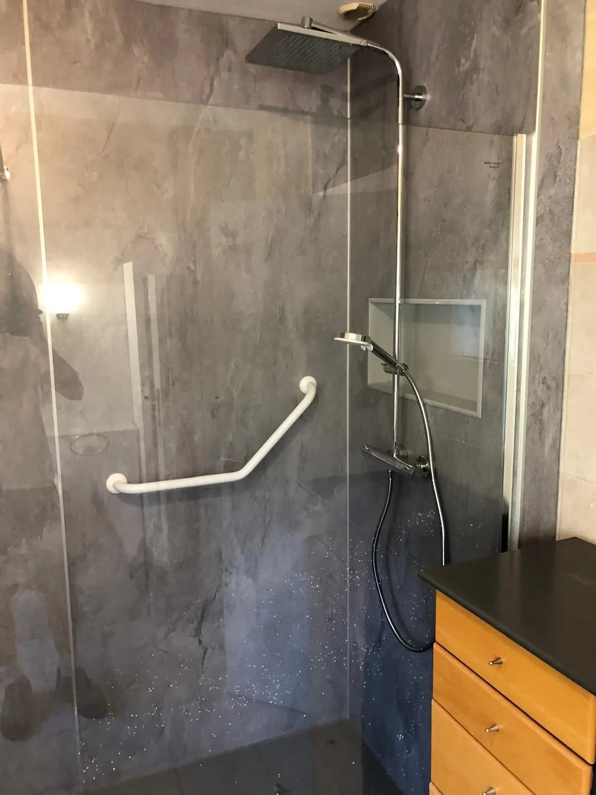 Douche en panneaux effet ardoise avec barre d’appui coudée blanche et paroi de verre