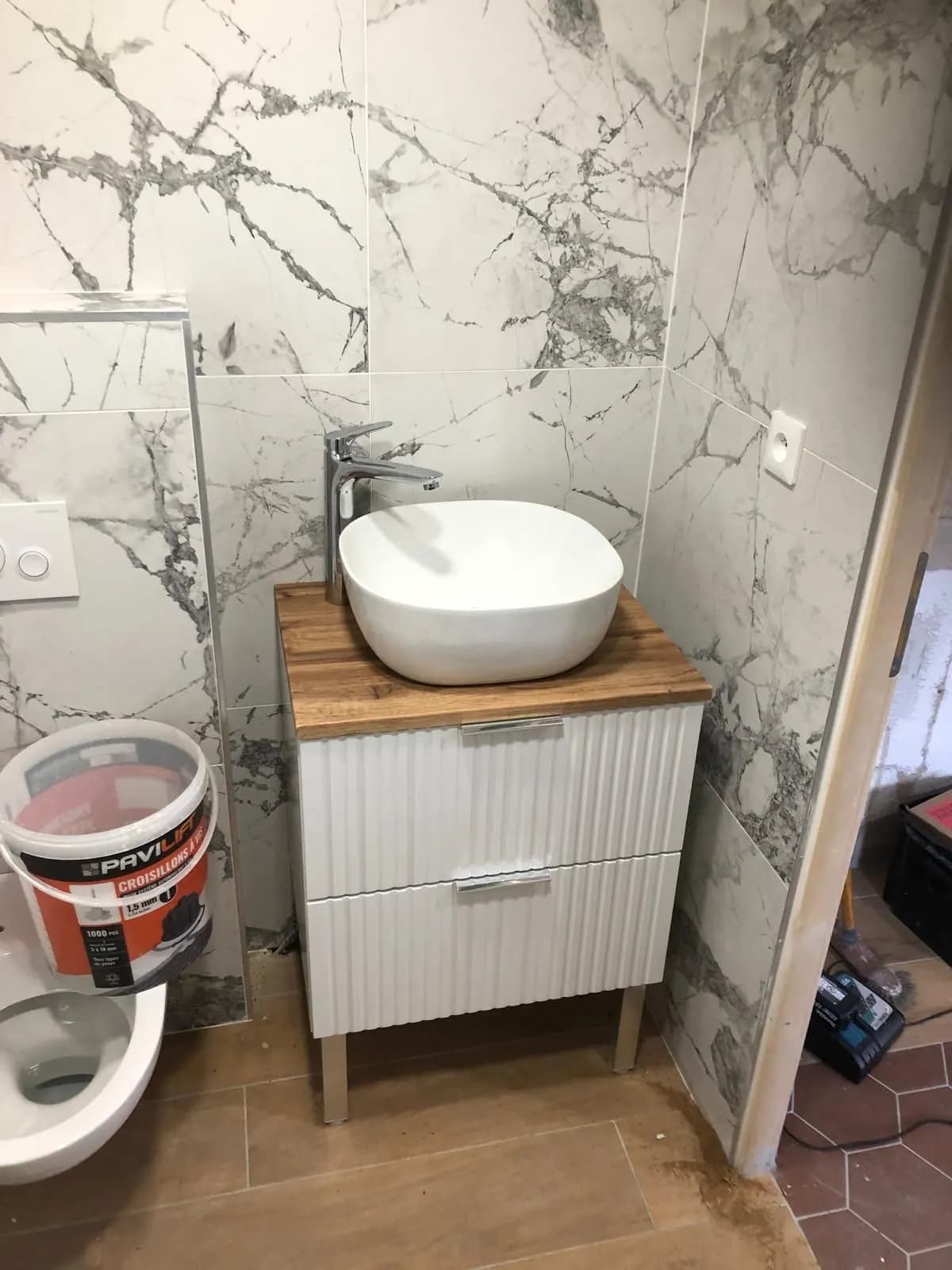 Vasque à poser sur meuble cannelé blanc, marbre veiné et WC suspendu