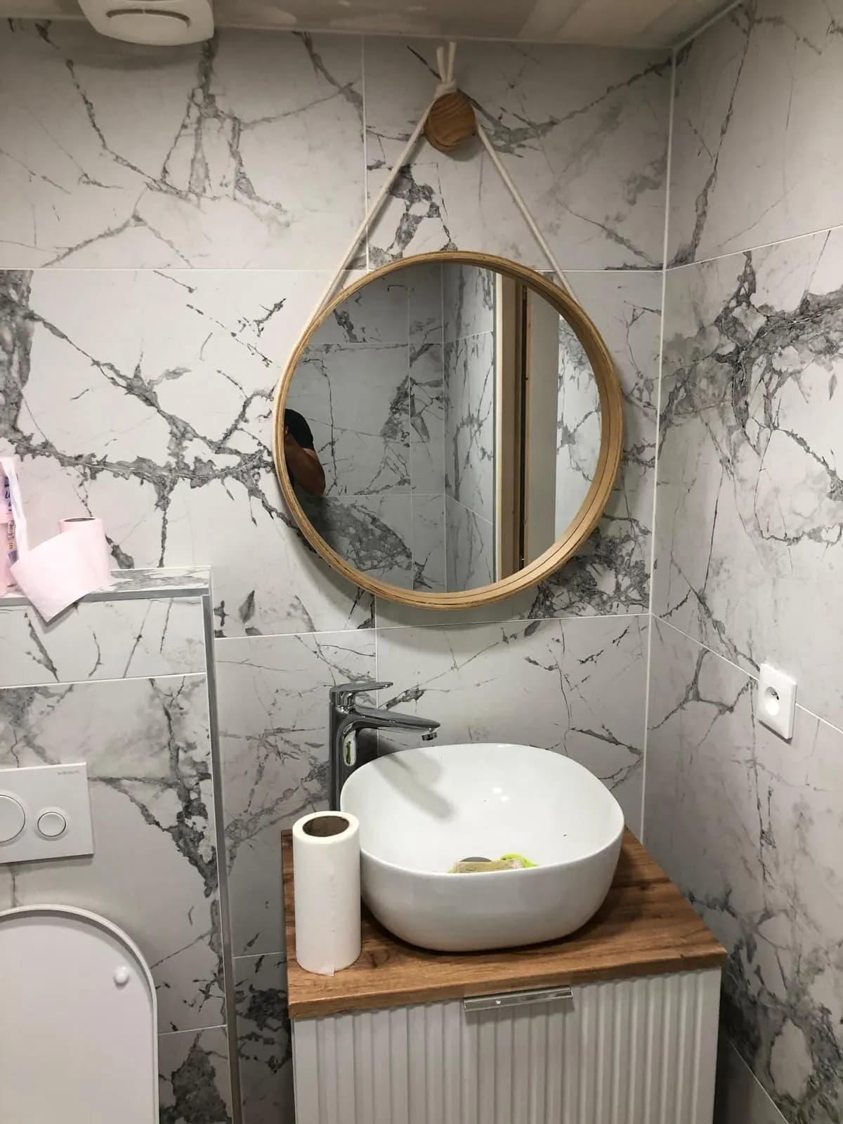 Vasque à poser et miroir rond à corde devant un mur en marbre veiné