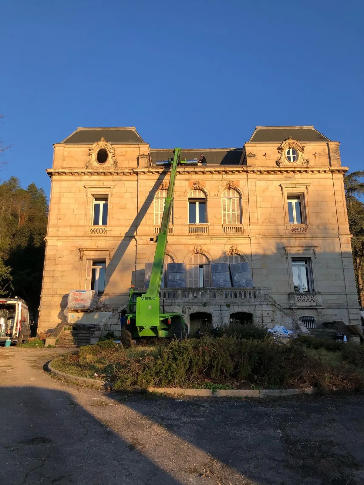 Chariot télescopique hissant des gaines de ventilation sur le toit d’un château
