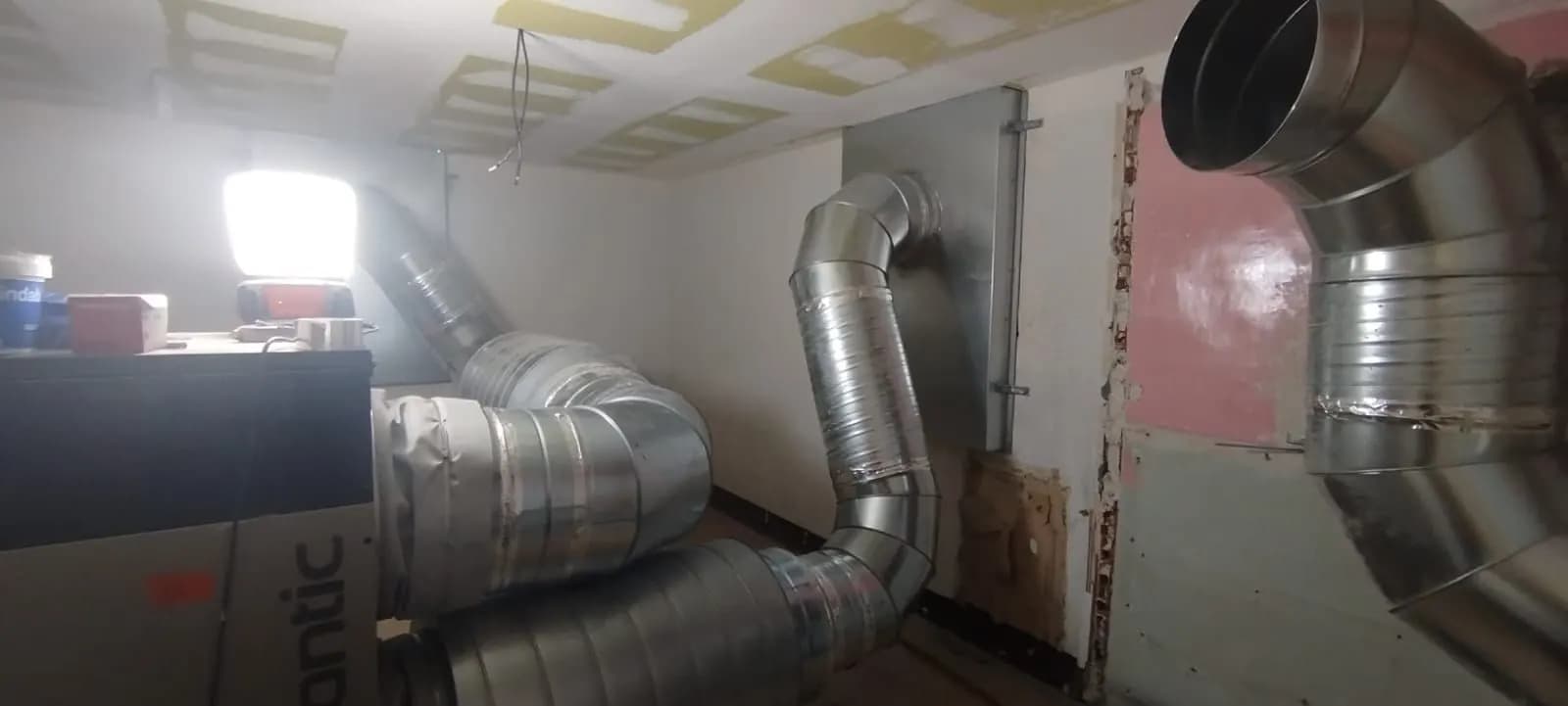Centrale de traitement d’air et gaines coudées dans une pièce en rénovation