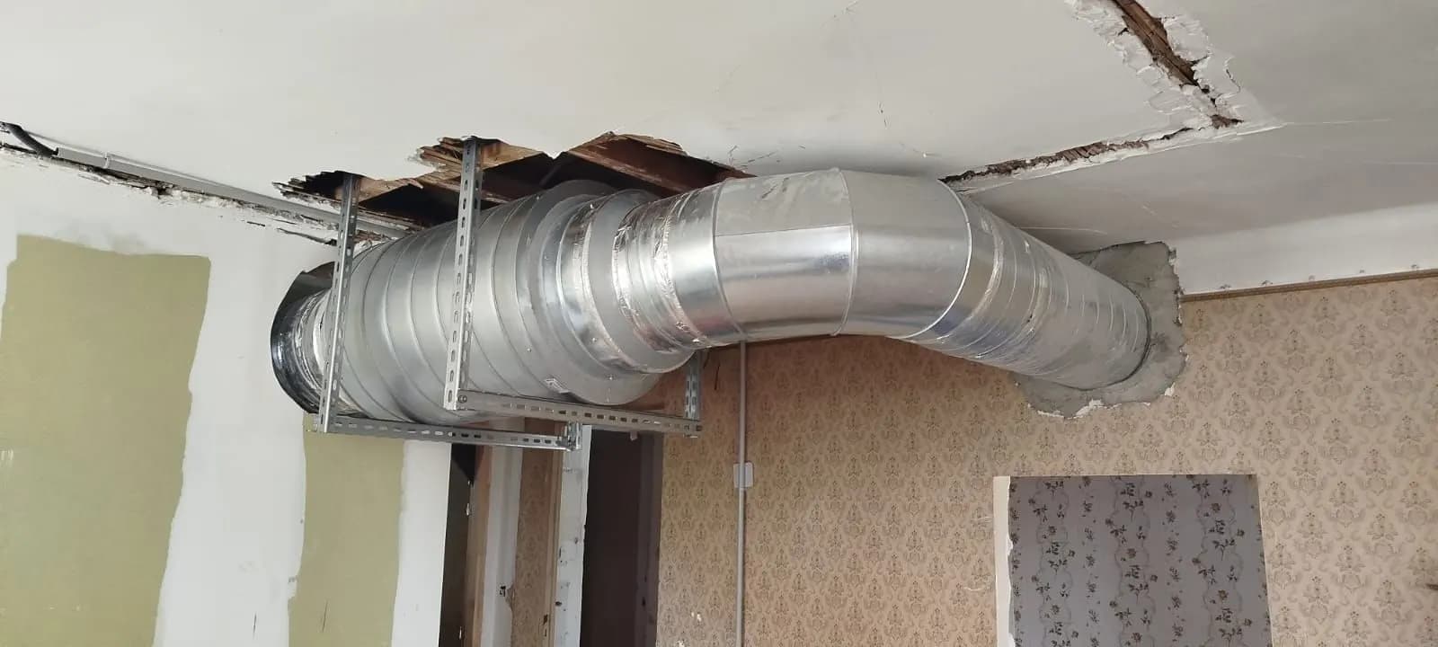 Gaine de ventilation traversant une cloison au-dessus d’un faux plafond ouvert