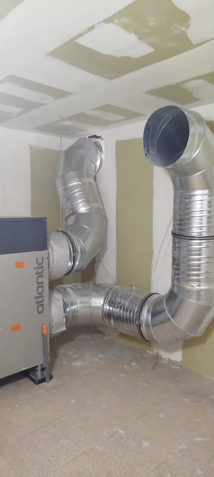 Centrale de traitement d’air et deux gaines montant dans un mur