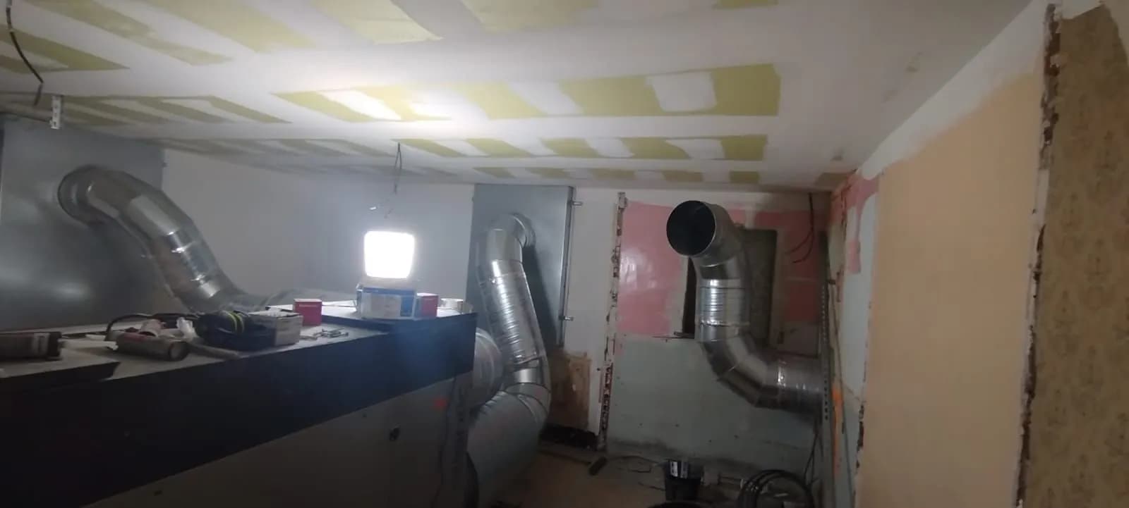 Centrale de traitement d’air et gaines dans une pièce aux murs décroûtés